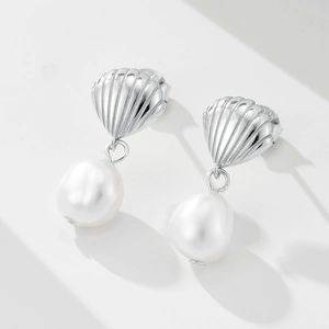 Detailed view of silver shell stud earrings with hanging white freshwater pearls