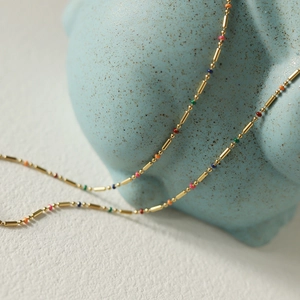 Detail of 18K gold plated rainbow bead necklace on a blue ceramic display prop