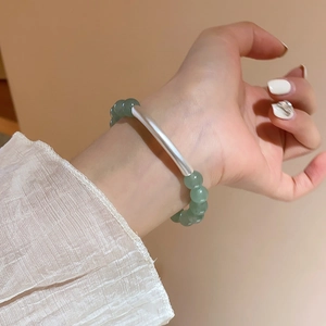 Close-up of green aventurine beaded bracelet with a silver curved tube on wrist