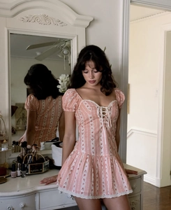 Detail of floral puff sleeve dress with lace trim and lace-up bodice on pink striped fabric