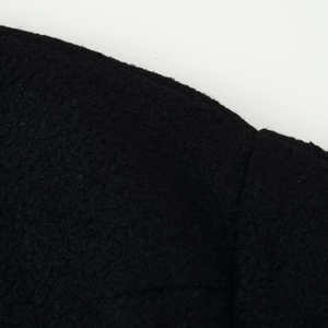 Black wool blend coat featuring asymmetric button closure and textured fabric surface