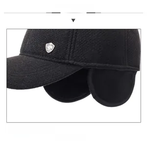 Detail view of winter baseball cap with ear flaps and shield-shaped metal emblem