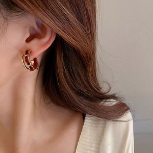Detail of velvet-woven gold chain C-shaped hoop earrings worn on a model
