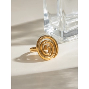 Detail view of gold spiral swirl ring with high-gloss finish on a minimal surface
