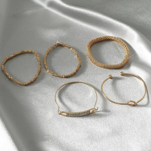 5-piece vintage gold bracelet set with rhinestones and knot designs on grey silk