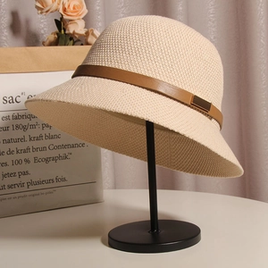 Détail du chapeau de soleil en paille beige avec ruban en cuir brun et boucle dorée
