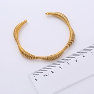 Detail view of gold wave bangle measuring 6cm inner diameter on a white background