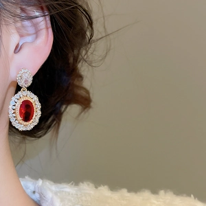 Close-up of vintage oval red gemstone earring with sparkling double-layer zircon frame