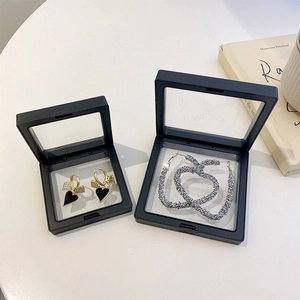 Macro view of two black PE film suspension boxes showing gold and silver earrings