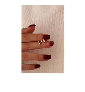 Detailed close-up showing tiny gold S925 silver stud earrings with zircon on a finger