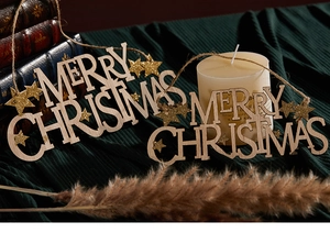Close-up of wooden Merry Christmas signs with gold stars on dark green fabric backdrop