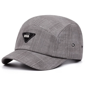 Detail of grey 5-panel cap featuring textured grid fabric and a black triangular metal logo