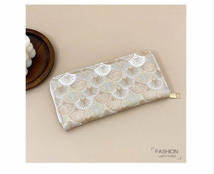 Detail of elegant long purse with golden shell embroidery and metal zipper puller