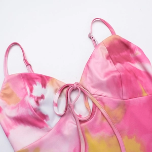 Detail of pink and yellow tie-dye satin dress featuring adjustable straps and a bow tie