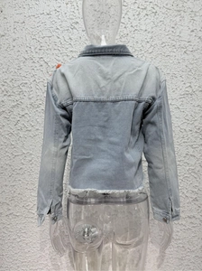 Detail of light blue denim jacket back with distressed frayed hem and panel stitching