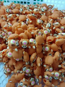 Pile of orange bear-shaped animal cable protectors in a production warehouse basket