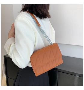 Detail of a brown quilted chain crossbody bag with silver hardware and PU leather texture