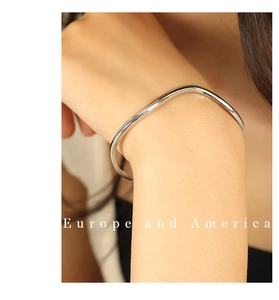 Détail d'un bracelet manchette vague en argent poli au design minimaliste sur le poignet