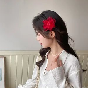 Détail d'une pince à cheveux camélia rouge en organza avec d'élégants bijoux en perles