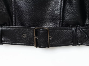 Detail of black pebbled leather jacket hem with silver buckle belt and fine stitching