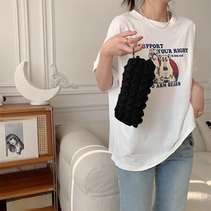 Detail of black popcorn textured pouch bag held by hand in a minimalist interior setting