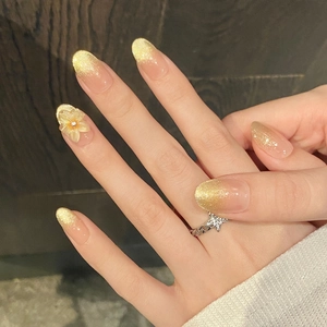 Detailed view of golden gradient press-on nails with 3D flower and elegant pearl accent