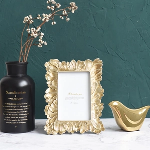 Golden embossed leaf photo frame with 10x15cm display on marble surface