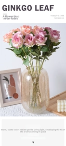 Pink purple silk rose bouquet in amber glass vase on a white minimalist desk