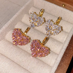 Détail macro de boucles d'oreilles cœur en zircon rose et blanc sur monture dorée