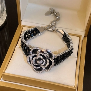 Detailed close-up of camellia flower bracelet with black beads and sparkling crystals