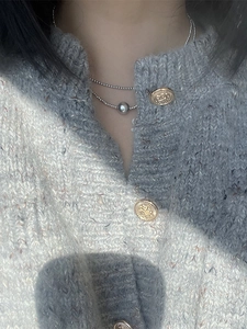 Close-up of layered silver beaded necklace on model with large round bead pendant