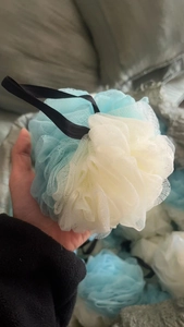 Detail shot of a large blue and beige dual-tone mesh bath sponge with a black hanging rope