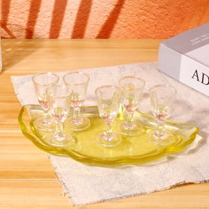 Vue détaillée de six verres à shooter avec un plateau de service en verre jaune ondulé