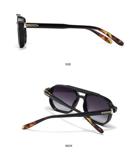 Detail of pilot sunglasses with bold black frames and gold T-logo on the temples