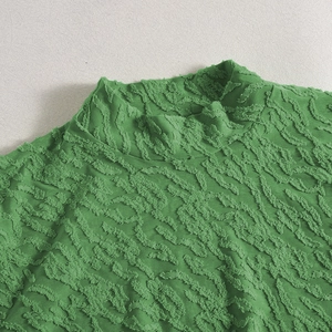Detailaufnahme des grünen Langarmkleids mit hochwertiger Beflockung und Ausschnitt-Design