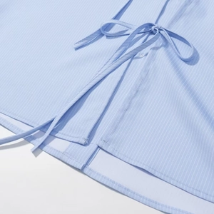 Close-up of light blue striped shirt featuring fabric tie details and clean stitching