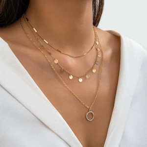 Close-up of gold triple-layered necklace with metal sequins and a pavé circle pendant