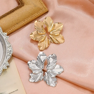 Vintage oversized gold and silver matte flower earrings on elegant orange satin background