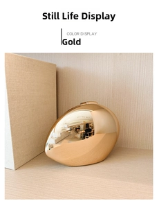 Detail of a golden oval evening clutch with a high-shine metallic mirror finish and sleek design