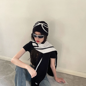 Close-up of black and white bow pattern knitted hat and scarf set on a model