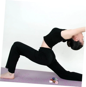 Bunte Naturkristallsteine auf einer lila bedruckten Yogamatte mit einer Yoga-Pose