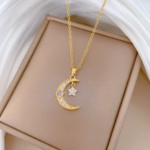 Détail du collier pendentif lune et étoile doré avec zircons brillants sur soie blanche
