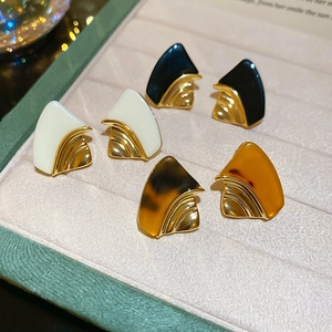 Detailed view of three pairs of geometric resin stud earrings in a luxury velvet jewelry box