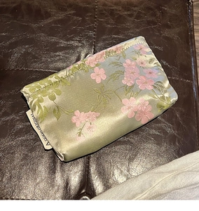 Detail of silk makeup bag with floral embroidery and A GOGO ORIGINAL woven label