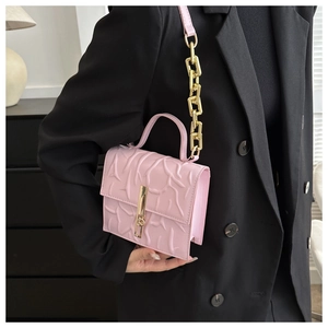 Detail of pink handbag featuring embossed coral texture and elegant gold chain strap