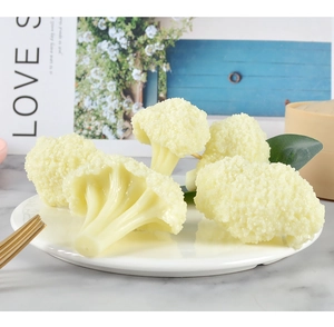 Macro shot of realistic cauliflower food model on a white plate with props and plant