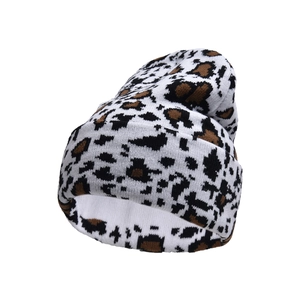 Close-up of thick knit texture and brown leopard cow print on a winter beanie hat