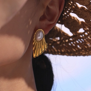 Elegant gold fan-shaped stud earrings with pearl accent worn in summer vacation style