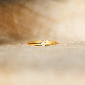 Macro shot of a minimalist gold ring featuring a sparkling heart-shaped zircon stone