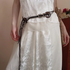 Detail of bohemian woven waist belt with resin flowers and tassels on white dress